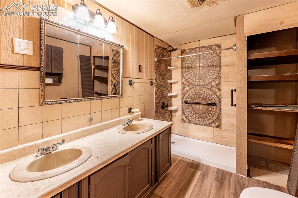 Image 19 of 30: Bathroom featuring a stall shower, double vanity, wood finished floors, and