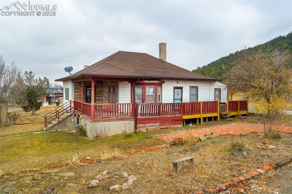 Image 2 of 30: View of front of home with a shingled roof, a chimney, and covered porch