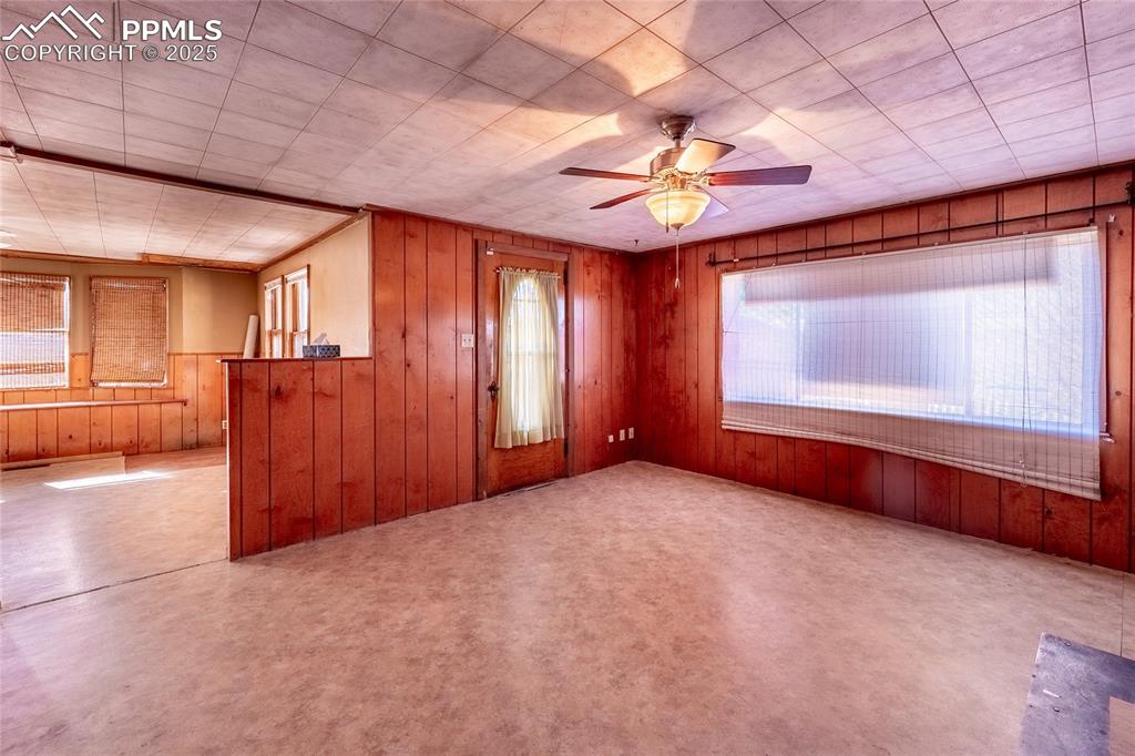Image 5 of 30: Spare room with a ceiling fan and wooden walls
