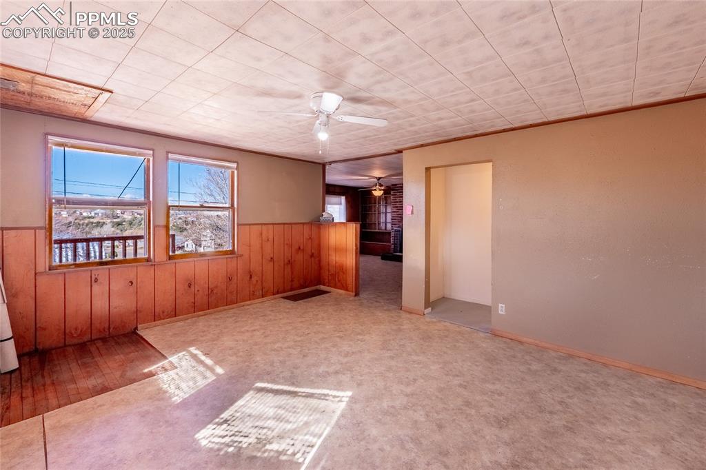 Image 7 of 30: Unfurnished room featuring wooden walls, ceiling fan, a wainscoted wall, an