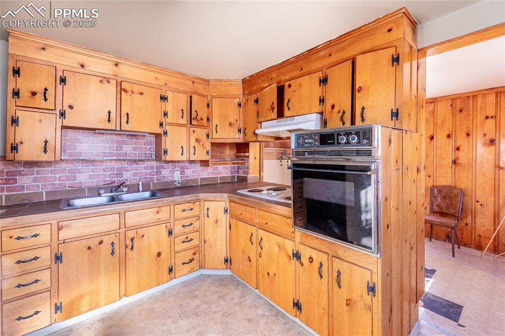 Image 8 of 30: Kitchen with oven, under cabinet range hood, decorative backsplash, white e