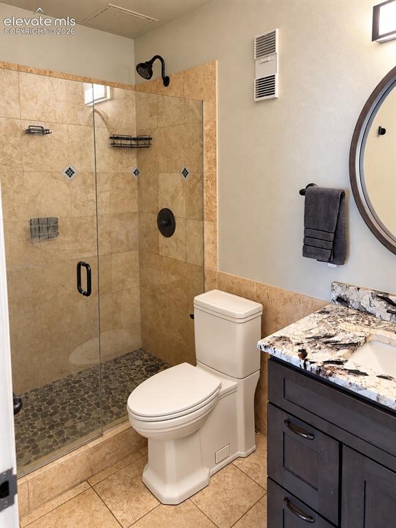Image 15 of 35: Glass-enclosed shower with stone tile surround and pebble flooring