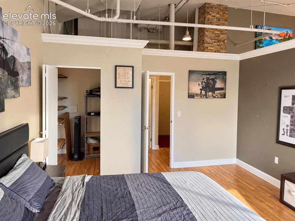 Image 20 of 35: Exposed ceiling pipes, wood-finish flooring, and a stone-clad column define