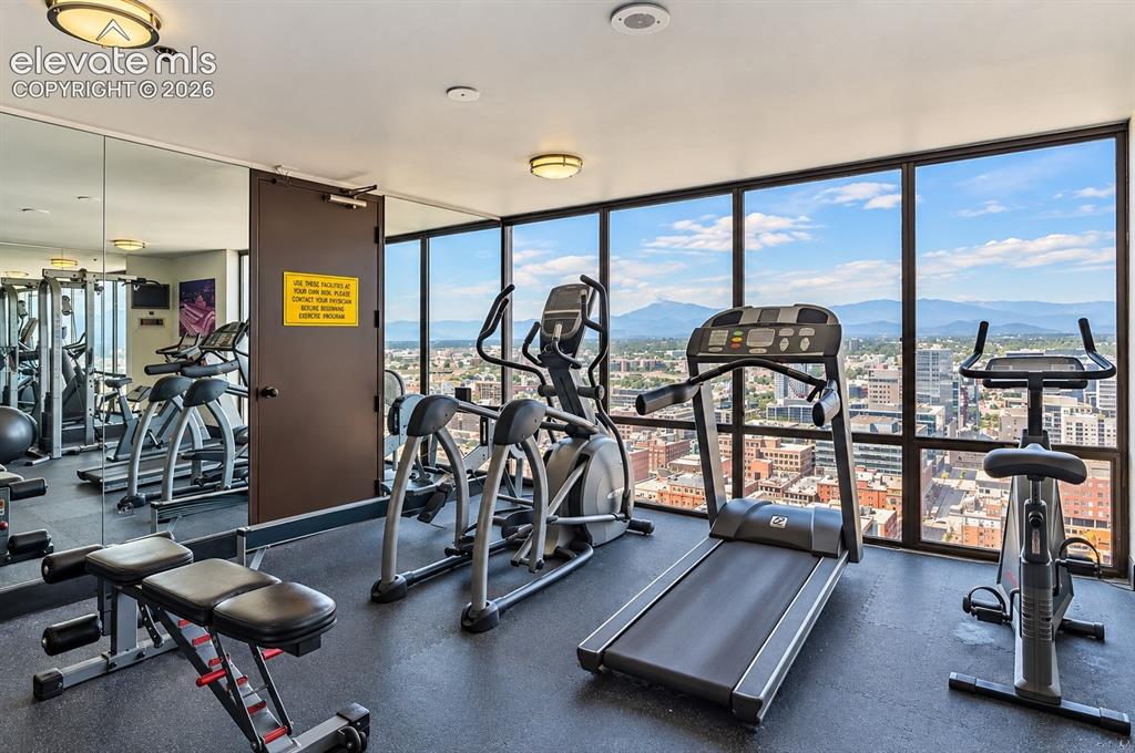 Image 23 of 35: Fitness center featuring floor-to-ceiling windows, city scenery, and mounta