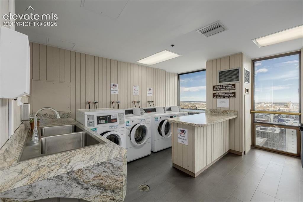 Image 24 of 35: Laundry facility featuring multiple washer and dryer units, a double basin 