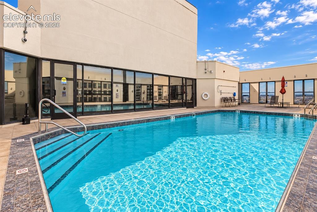 Image 26 of 35: Outdoor swimming pool with integrated steps, surrounded by tile decking and