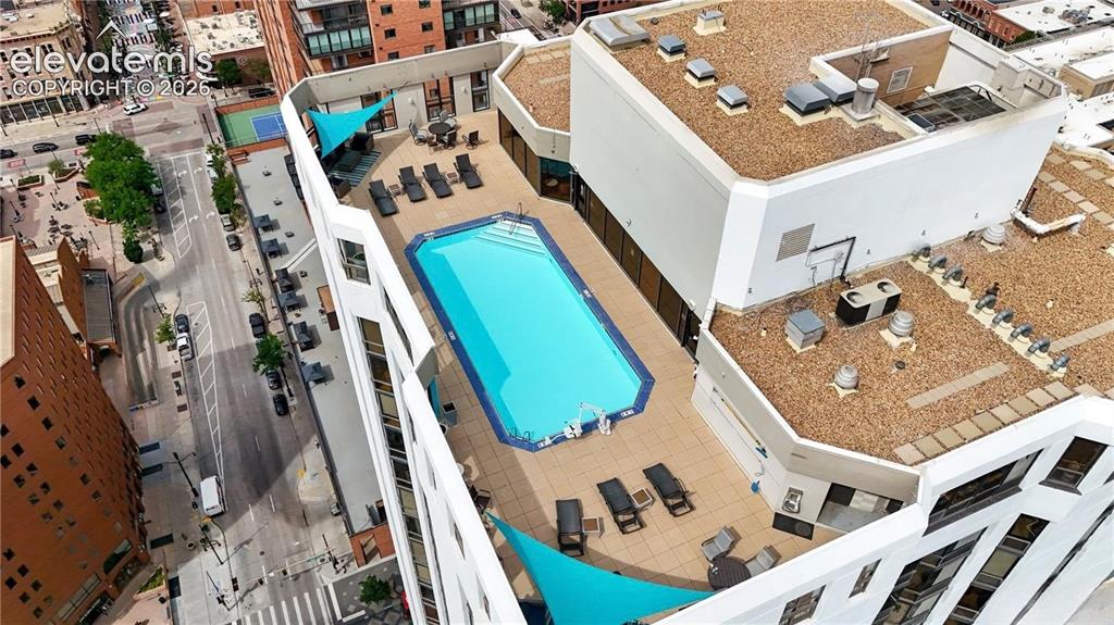 Image 28 of 35: Rooftop swimming pool with a surrounding paved deck, complemented by shade 