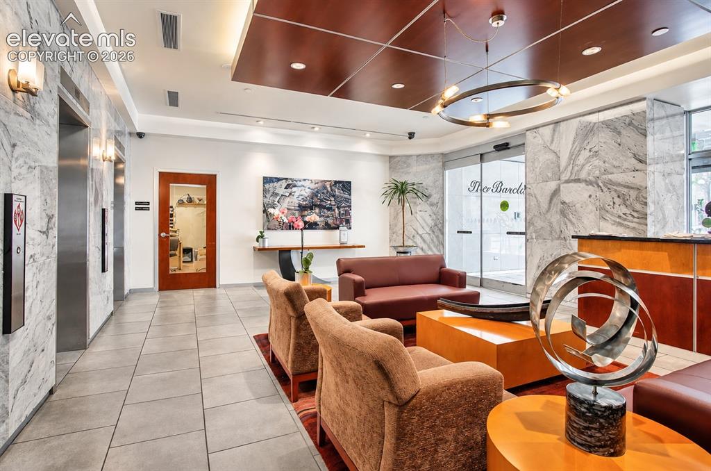 Image 31 of 35: Lobby featuring marble-clad walls, recessed lighting, and a wood-paneled ce