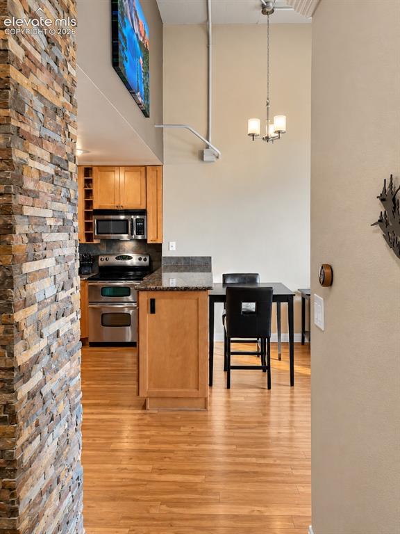 Image 6 of 35: Stone-clad architectural column, wood-finish flooring, kitchen featuring st