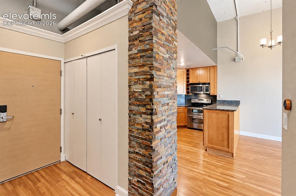 Image 7 of 35: Stone-clad architectural column, wood-finish flooring, kitchen with stainle