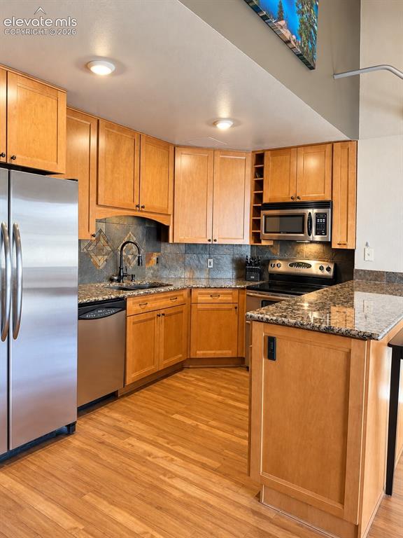 Image 9 of 35: Kitchen with wood-finish flooring, recessed lighting, and stainless steel a