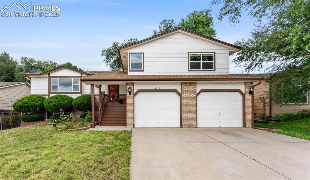 Caption: View of front of home with brick siding, concrete driveway, and a front lawn