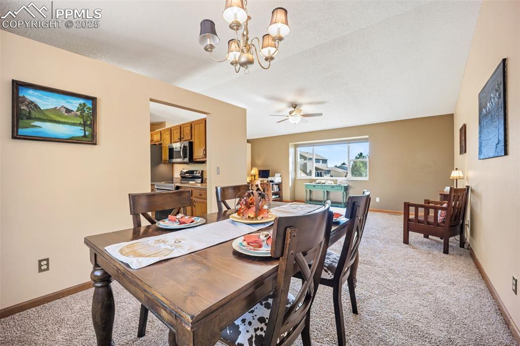 Image 11 of 47: Dining area featuring a chandelier, light carpet, a ceiling fan, and a text