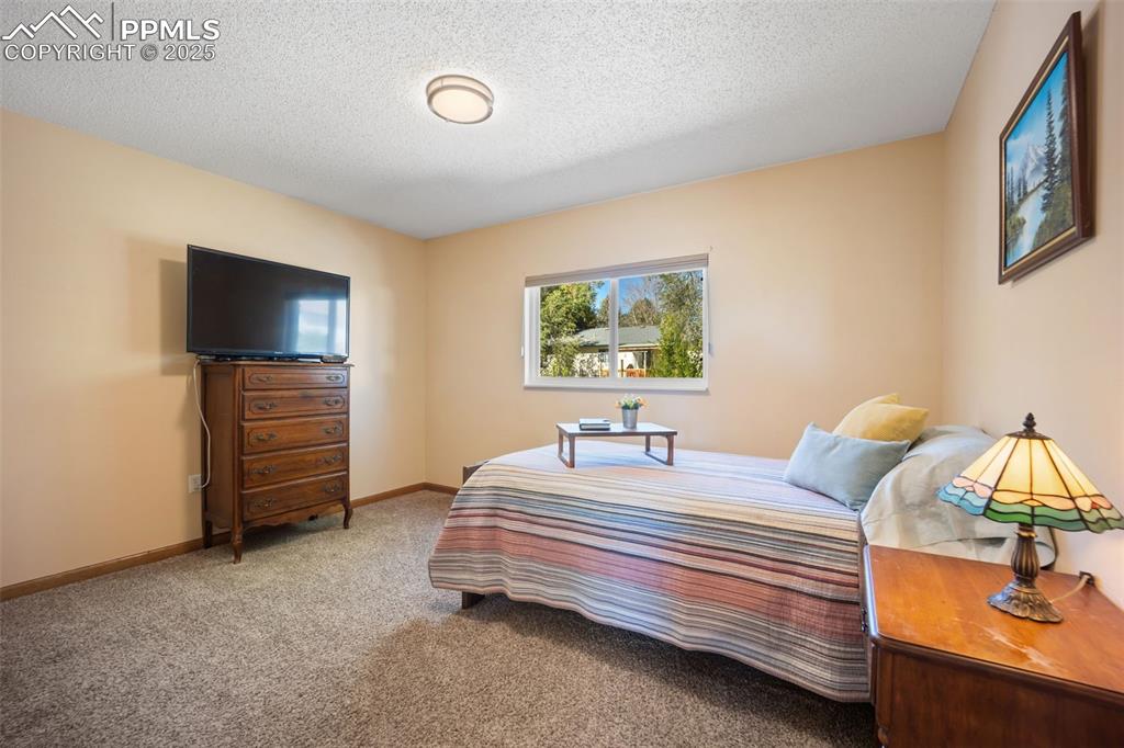 Image 16 of 47: Carpeted bedroom featuring a textured ceiling and baseboards