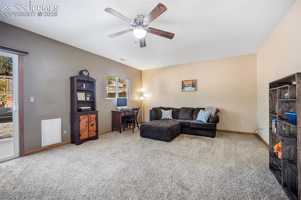 Image 22 of 47: Living area featuring light carpet and ceiling fan