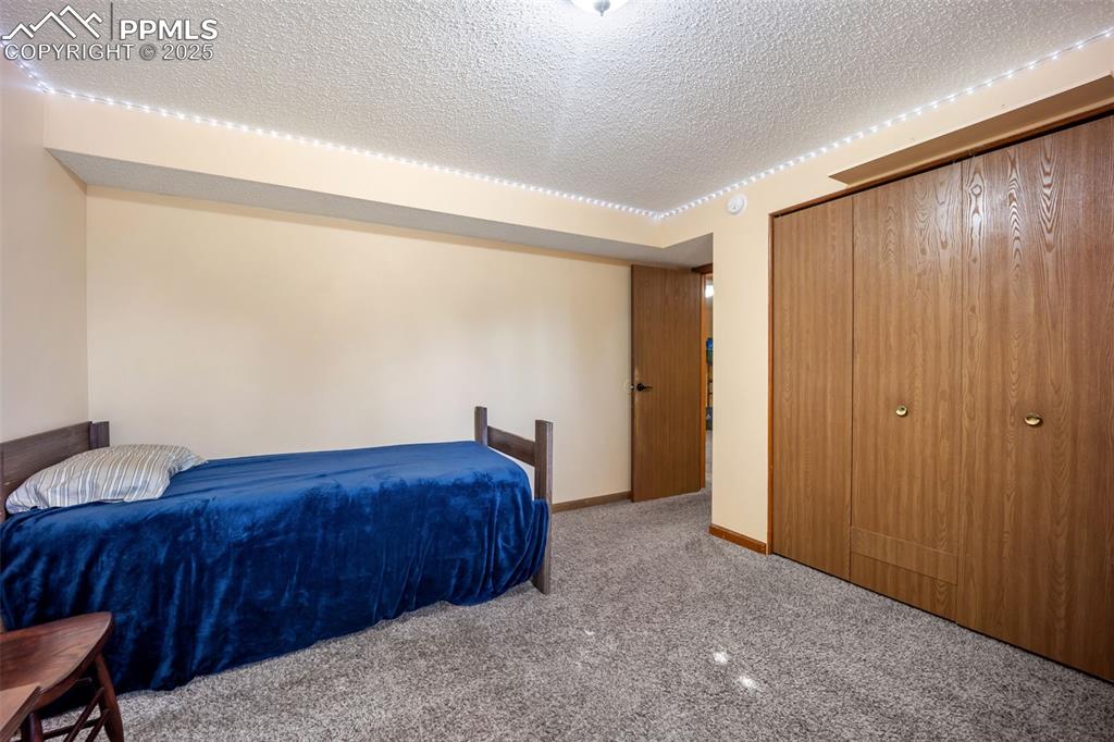 Image 31 of 47: Carpeted bedroom with a textured ceiling and baseboards