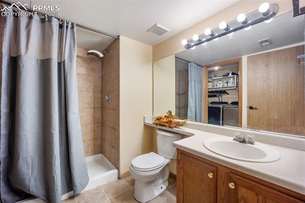 Image 32 of 47: 3/4 bathroom with vanity, a stall shower, and light tile patterned floors
