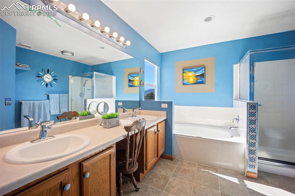 Image 4 of 47: Bathroom featuring a shower stall, double vanity, a garden tub, and light t