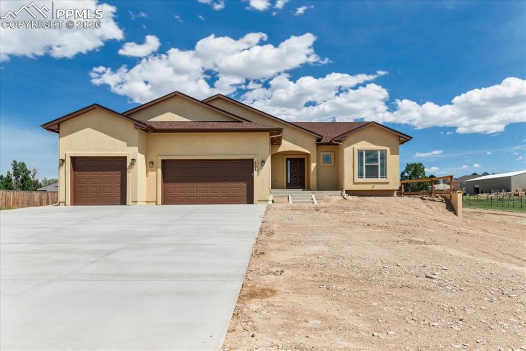 Caption: View of front of house featuring stucco siding, a garage, and concrete driveway