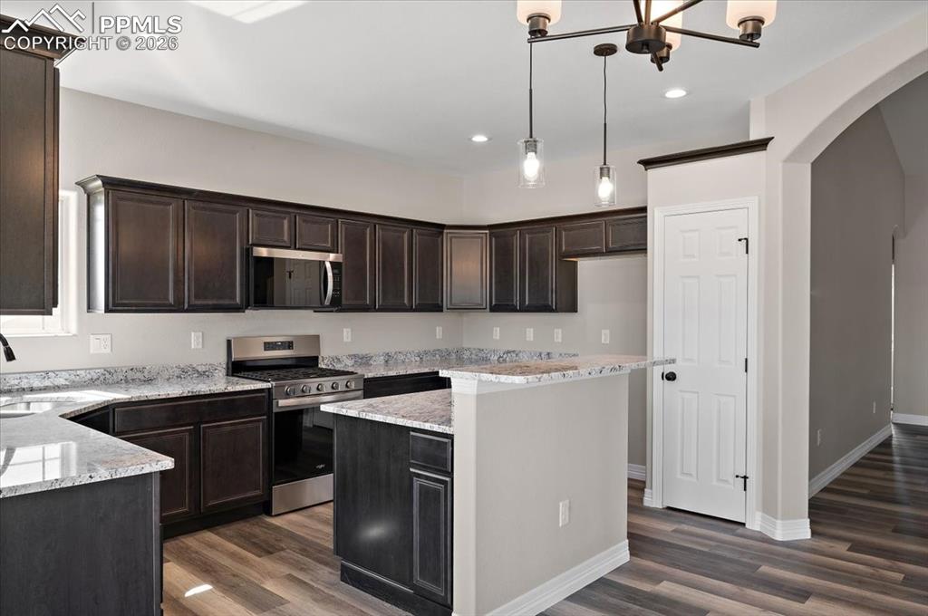 Image 10 of 40: Kitchen featuring stainless steel appliances, dark brown cabinetry, light s