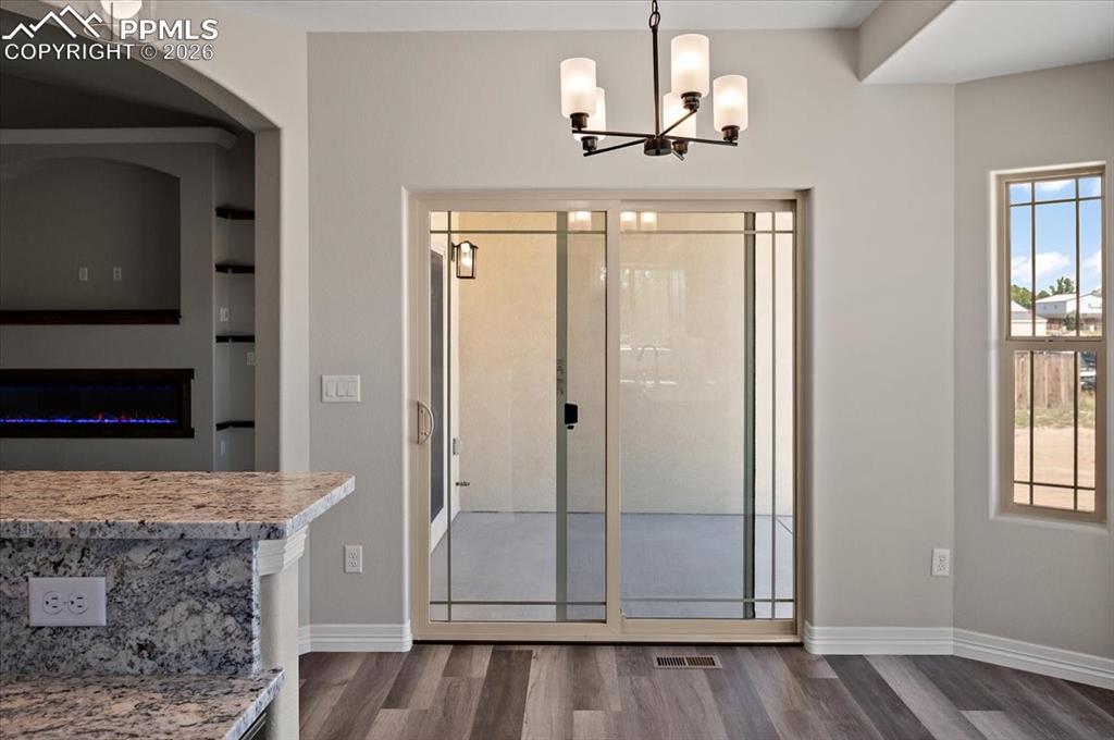 Image 14 of 40: Entryway with dark wood-style flooring, a glass covered fireplace, and a ch