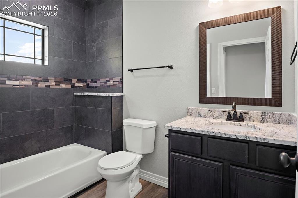 Image 16 of 40: Full bath featuring vanity, dark wood-type flooring, a textured wall, and b