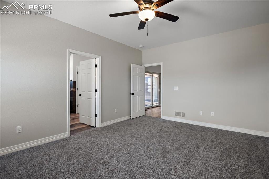 Image 20 of 40: Unfurnished bedroom with dark colored carpet and a ceiling fan