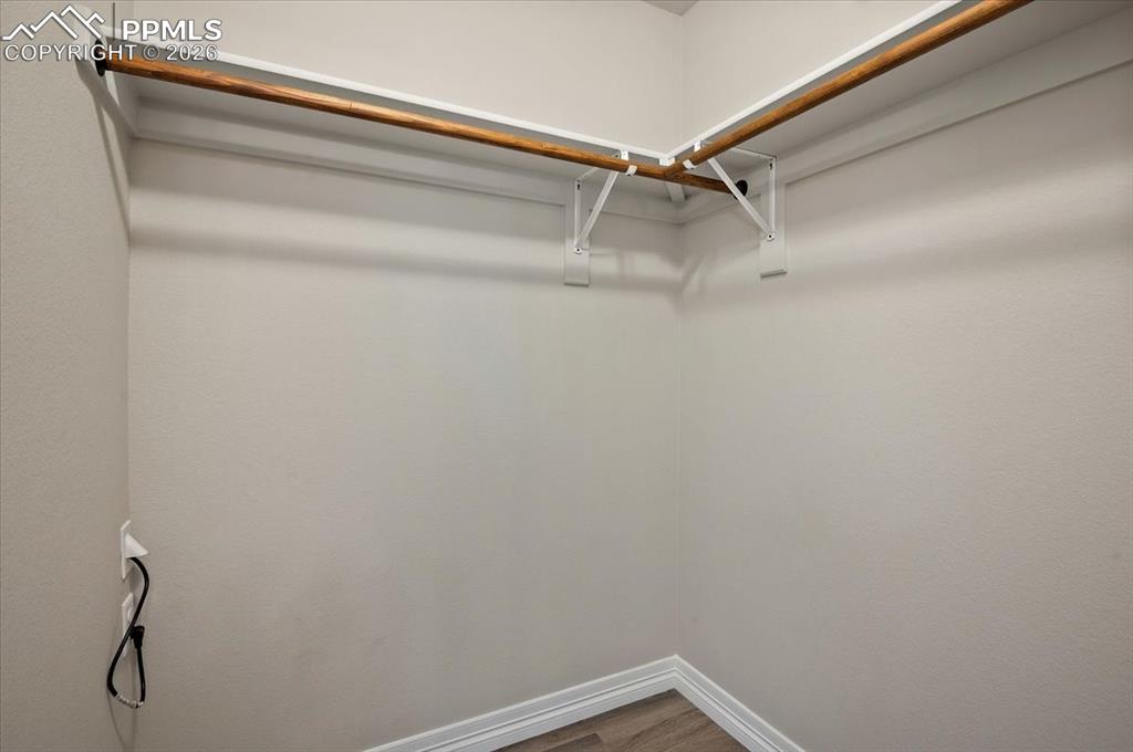 Image 22 of 40: Walk in closet with wood finished floors