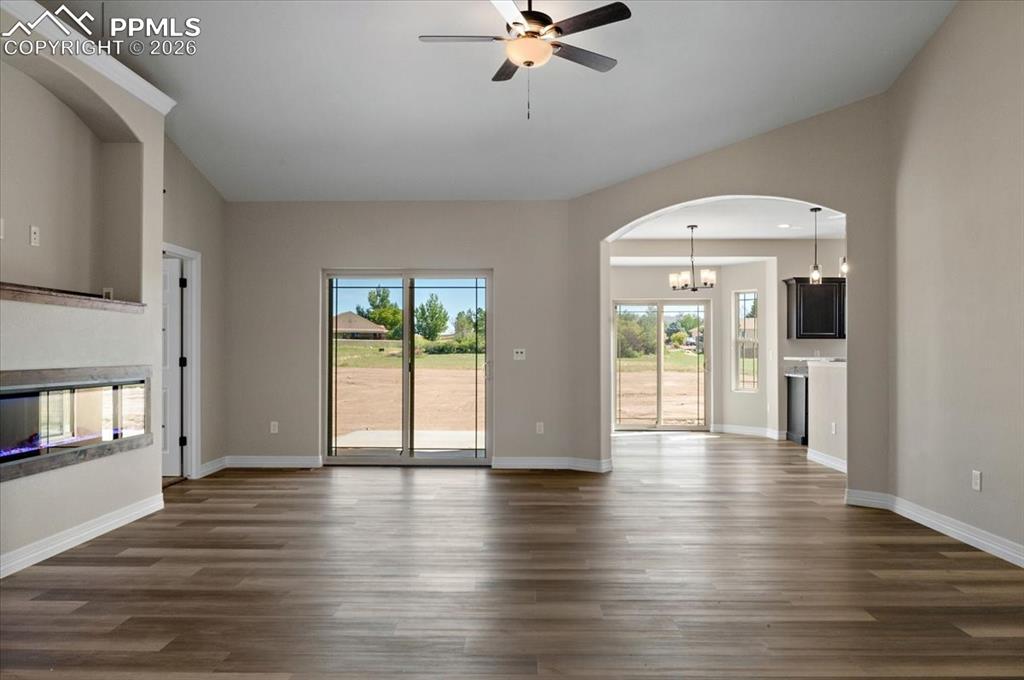 Image 3 of 40: Unfurnished living room featuring arched walkways, a multi sided fireplace,