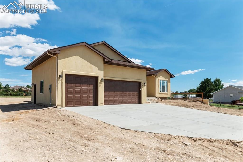 Image 40 of 40: Ranch-style house featuring stucco siding, driveway, and a garage