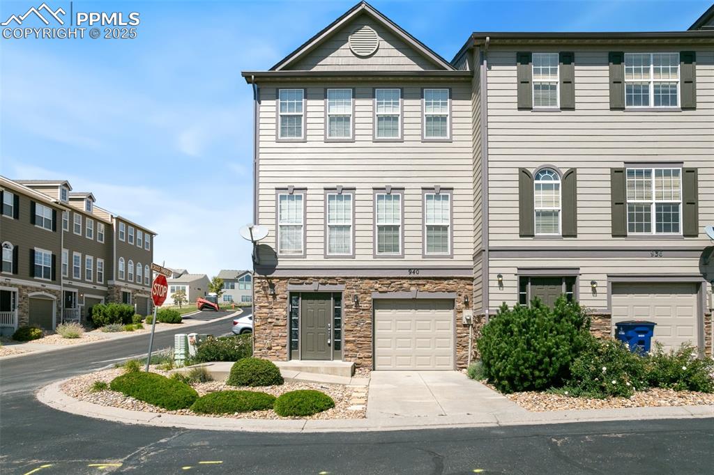 Caption: View of front of house featuring stone siding, concrete driveway, an attached garage, and a resident