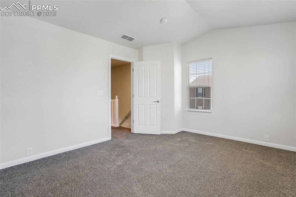 Image 17 of 28: Carpeted empty room featuring baseboards and vaulted ceiling