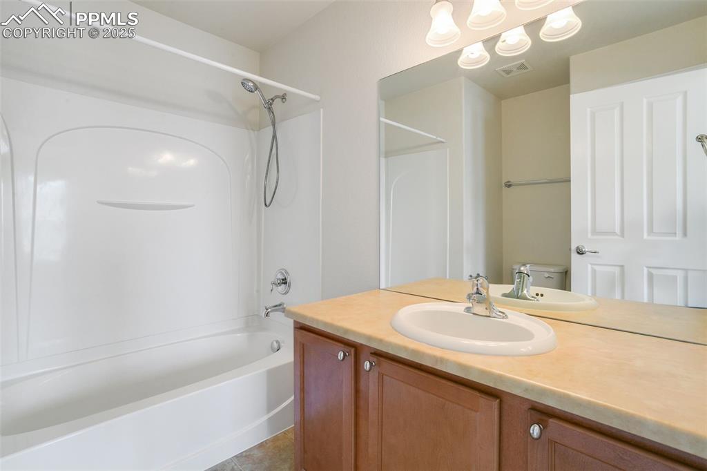 Image 18 of 28: Bathroom featuring shower / tub combination, vanity, and light tile pattern