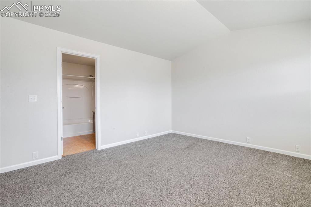 Image 22 of 28: Unfurnished bedroom featuring vaulted ceiling, light carpet, and connected 