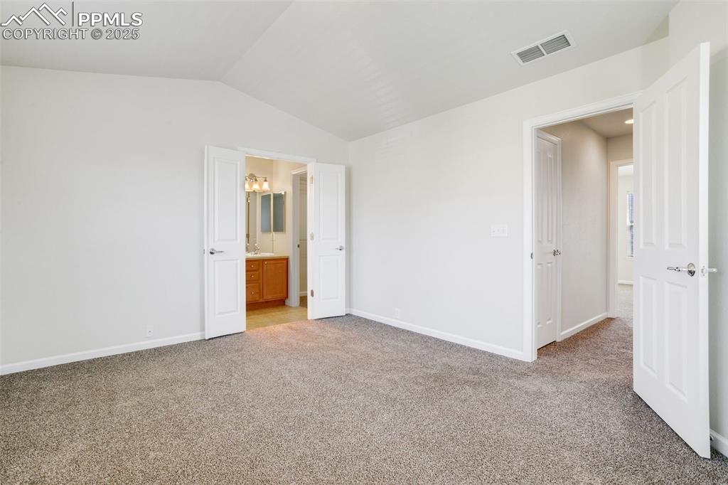 Image 23 of 28: Unfurnished bedroom featuring light colored carpet, lofted ceiling, and con