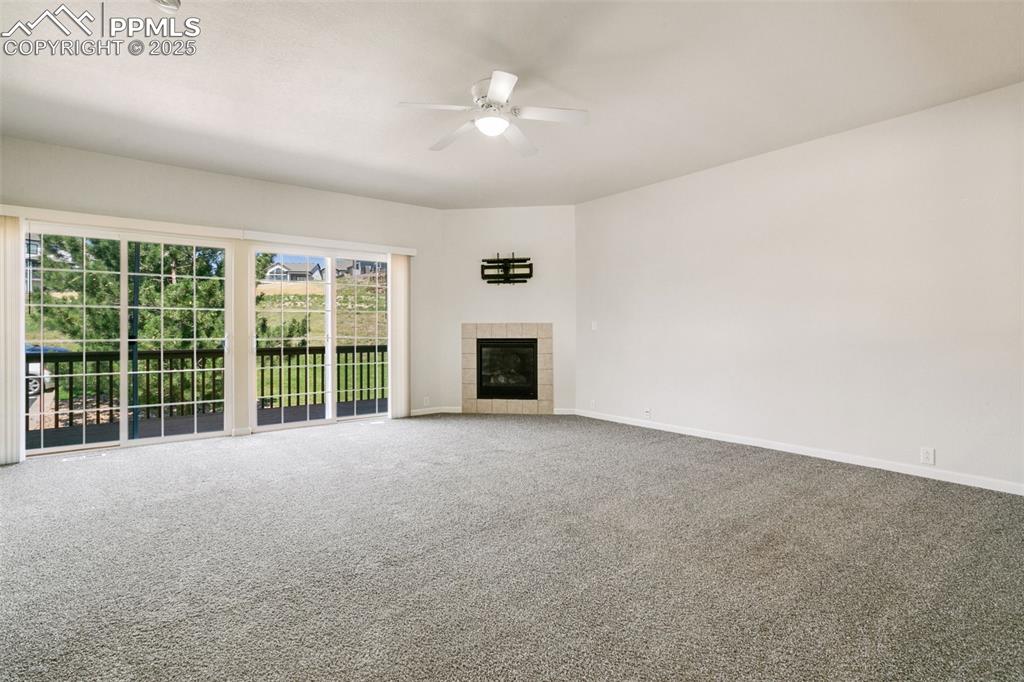 Image 4 of 28: Unfurnished living room featuring a tile fireplace, carpet, and a ceiling f