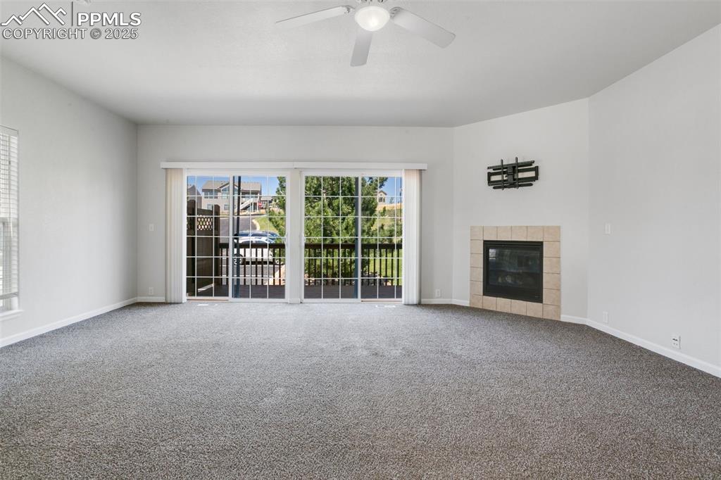 Image 8 of 28: Unfurnished living room with carpet floors, a tile fireplace, and a ceiling