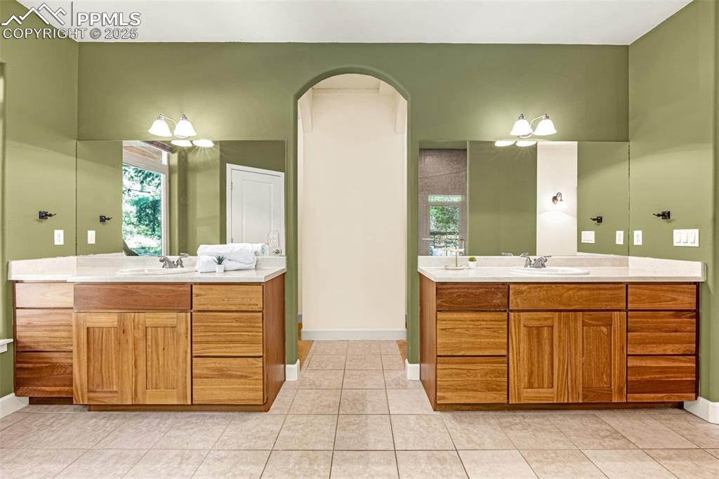 Image 16 of 41: Full bathroom featuring two vanities, baseboards, and tile patterned floors