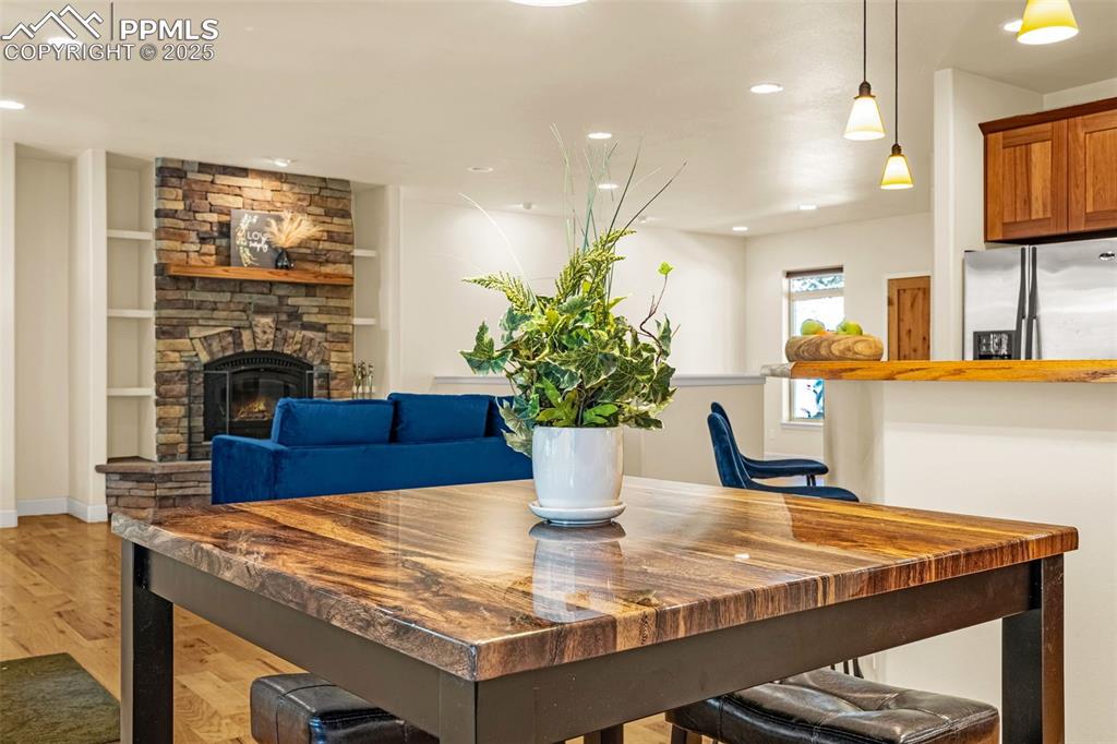 Image 28 of 41: Dining area with light wood-style flooring, recessed lighting, a stone fire
