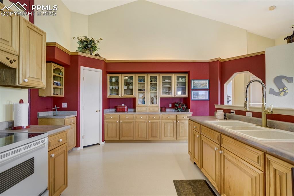 Image 10 of 50: Kitchen with white electric range, glass insert cabinets, light brown cabin