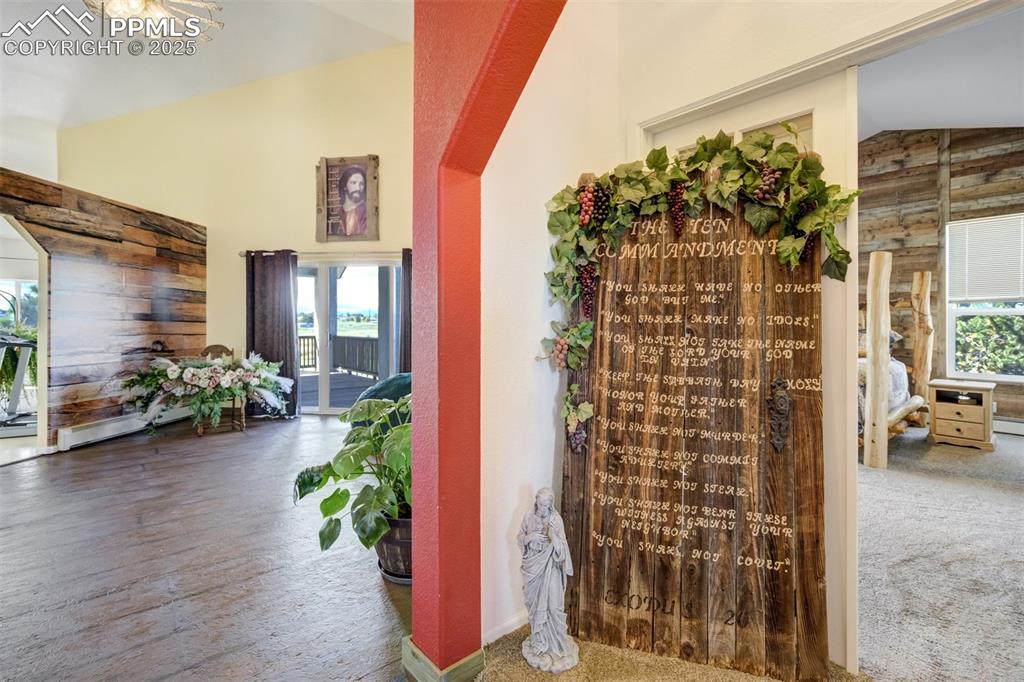 Image 12 of 50: Wine cellar featuring wooden walls, carpet, and high vaulted ceiling