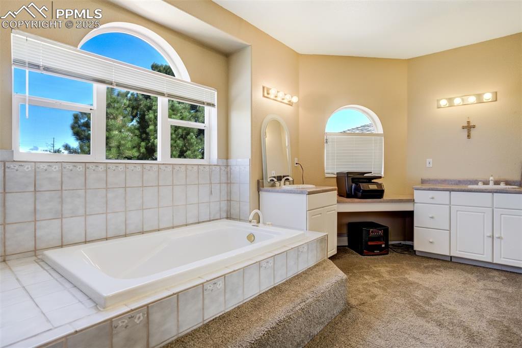Image 15 of 50: Bathroom featuring vanity, a garden tub, and light colored carpet