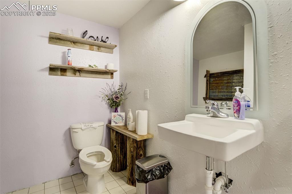 Image 23 of 50: Half bathroom featuring light tile patterned floors and a textured wall