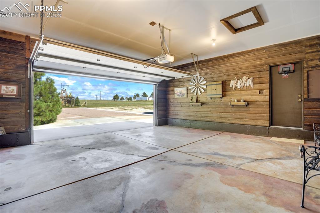 Image 32 of 50: Garage with wood walls and a garage door opener