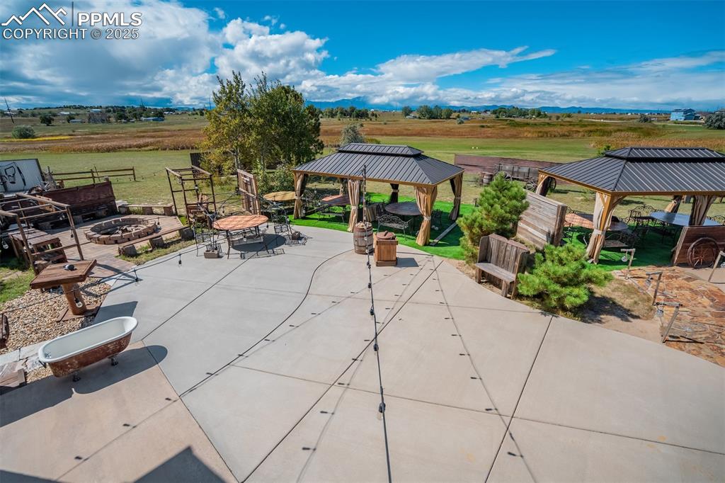 Image 34 of 50: View of patio with a gazebo, a fire pit, and a view of countryside