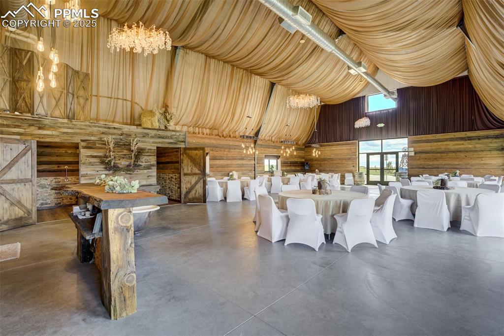 Image 47 of 50: Event Center with a chandelier, finished concrete flooring, wooden walls, a