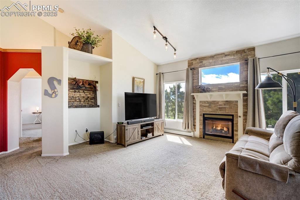 Image 6 of 50: Living room with light carpet, a fireplace, a baseboard radiator, high vaul