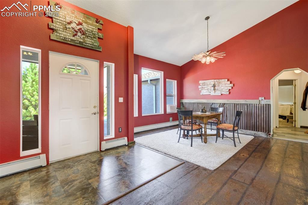 Image 7 of 50: Dining area with high vaulted ceiling, baseboard heating, arched walkways,