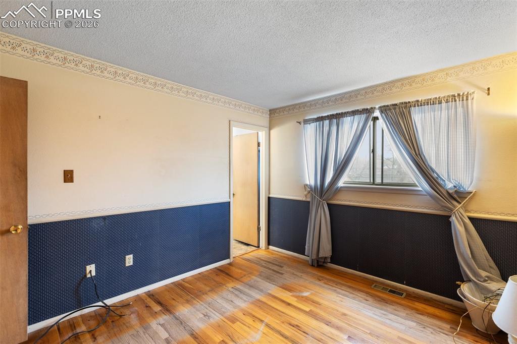 Image 19 of 34: Primary bedroom features real wood flooring, and an adjoining 3/4 bathroom