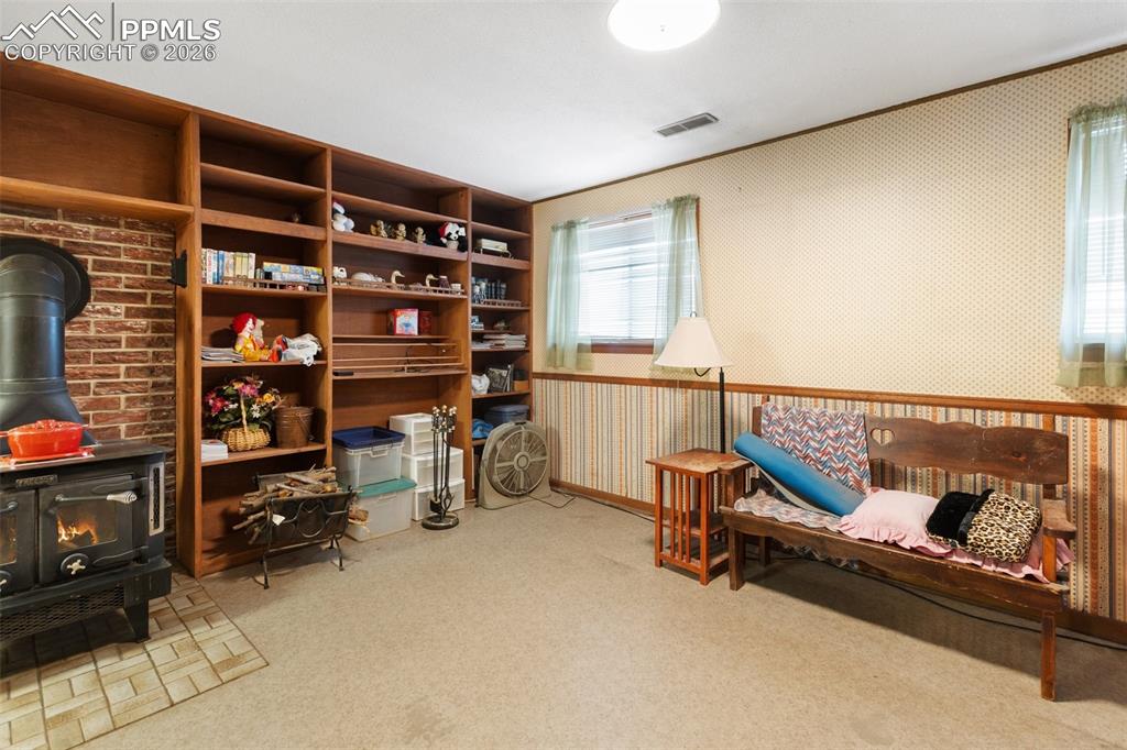 Image 29 of 34: Basement family room with wood burning stove and built-in shelves